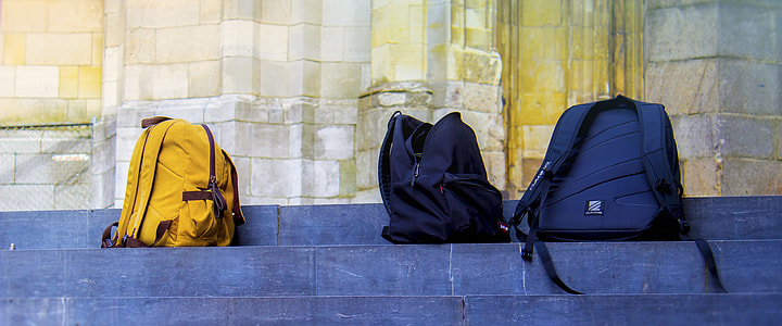 three blue-yellow-and-gray backpack on gray concrete stair during daytime thumbnail