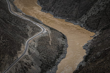 bird's eyeview photo of gray pavement near raging body of water thumbnail
