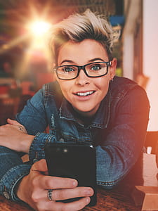 smiling woman wearing blue denim button-up jacket and black framed eyeglasses holding jet black iPhone 7 Plus thumbnail