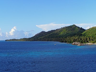 blue ocean water beside green mountain under blue sky thumbnail