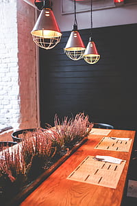 three round gray pendant lamps turned on above rectangular brown wooden table thumbnail