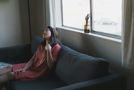 woman sitting on gray fabric sofa beside gray framed clear glass window during daytime thumbnail