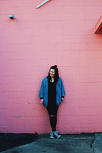 woman leaning on pink concrete painted wall thumbnail