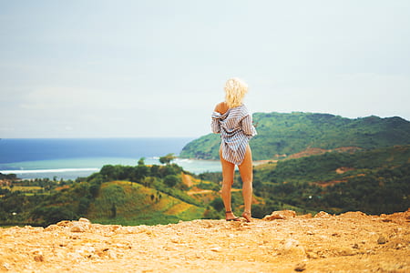 woman standing on brown soil looking at mountains during daytime thumbnail