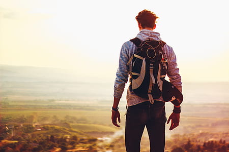 man wearing black and white backpack standing against light at daytime thumbnail