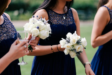 two women holding white petaled flowers thumbnail