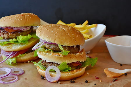 two burgers and fries on brown wooden top table thumbnail