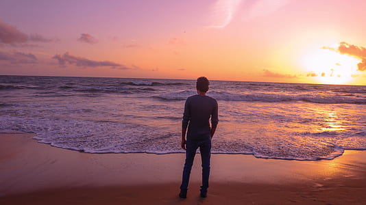 man standing on seashore during golden hour thumbnail