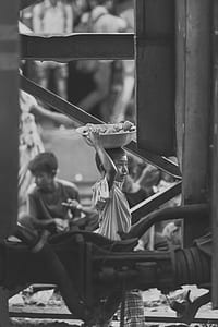 grayscale photography of boy carrying basin using his head thumbnail