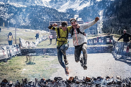two men jumping together over the burning firewood thumbnail