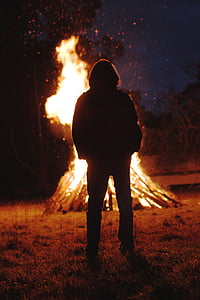 silhouette of person standing in front of bonfire thumbnail