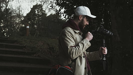 person holding camera tripod while looking at camera thumbnail