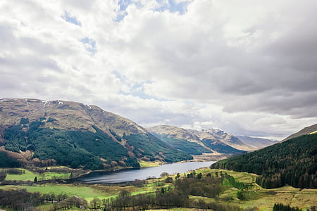 body of water in between mountains under white clouds at daytime thumbnail