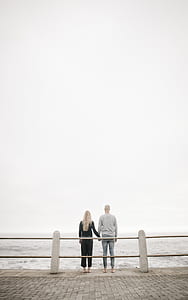 couples holding hands outside fence facing body of water at daytime thumbnail