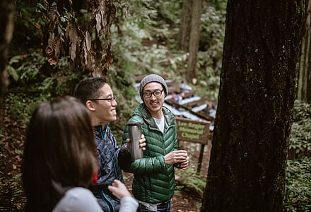 smiling two men standing surrounded by trees during daytime thumbnail
