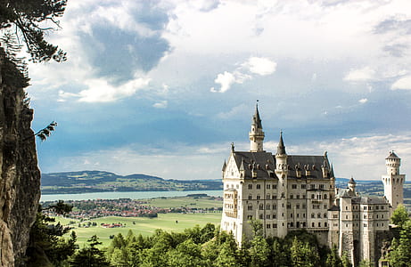 bird's-eye view of white concrete castle beside green trees under cloudy sky thumbnail