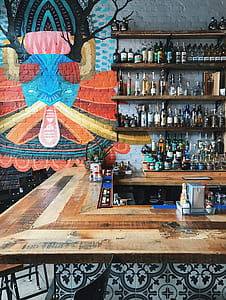 liquor bottles on wall shelf near corner desk thumbnail