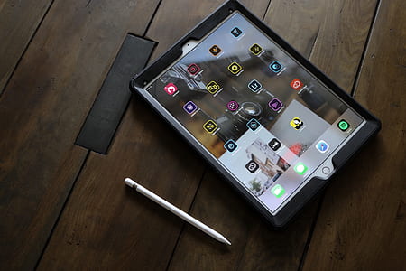 silver iPad turned on in black case beside Apple Magic Pencil thumbnail