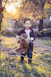 boy carrying brown teddy bear near brown rope during daytime thumbnail