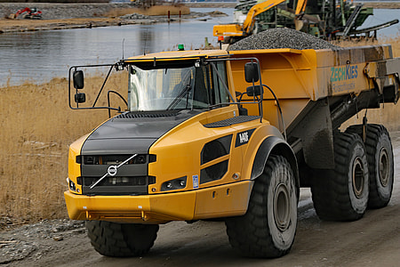 yellow and black Volvo dump truck on road near river thumbnail