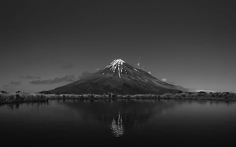 grayscale photo of mountain lava eruption and body of water thumbnail