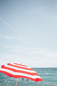 A beach umbrella with people swimming in the background thumbnail