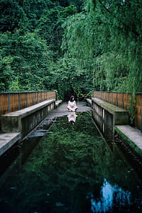woman sitting on concrete bridge near forest at daytime thumbnail