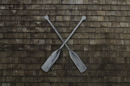 two brown wooden boat paddles on brown brick wall thumbnail