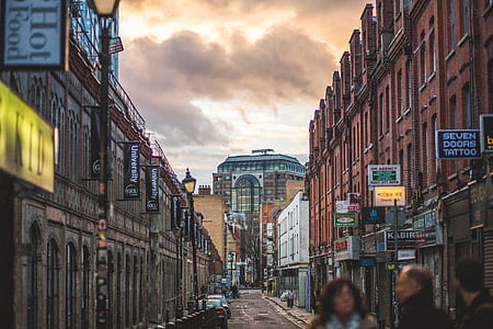 Person on Road Between Brown Walled Building during Daytime Under Cumulus Clouds thumbnail