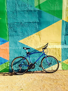 blue commuter bike parked beside murals during daytime thumbnail