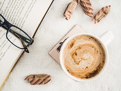 cup of coffee beside book with black framed eyeglasses thumbnail