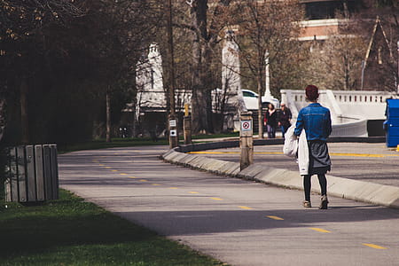 Woman Wearing Blue-washed Denim Jacket Walking On Street thumbnail