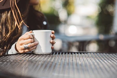 focus photography of woman holding white ceramic mug during daytime thumbnail