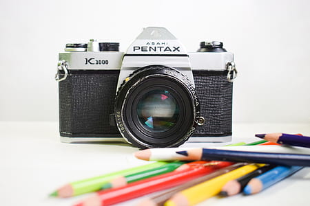 assorted-color pens near gray Pentax DSLR camera thumbnail