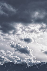 landscape photography of black and gray mountain range under cloudy sky thumbnail