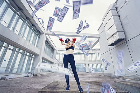 woman holding two red money gun time lapse photography between two concrete buildings thumbnail