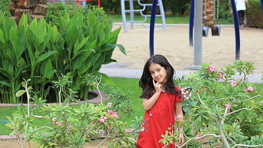girl in red dress standing near green leafed plant during daytime thumbnail