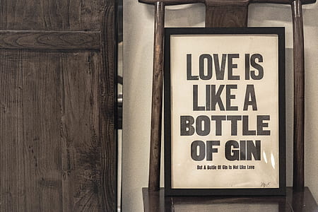 love is like a bottle of gin framed signage beside brown wooden door thumbnail