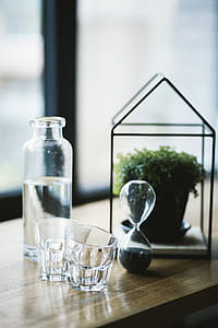 Shot Glasses and Hourglass on Brown Wooden Surface thumbnail