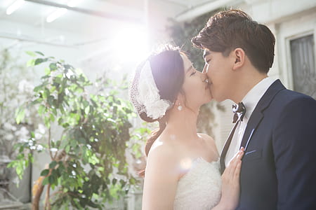 woman kissing man near green leafed plant thumbnail