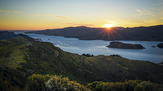body of water surrounded by mountains during golden hour time thumbnail