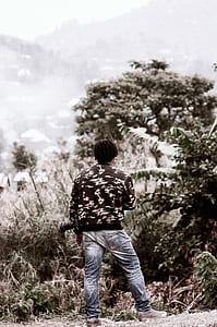 man standing facing trees during day thumbnail