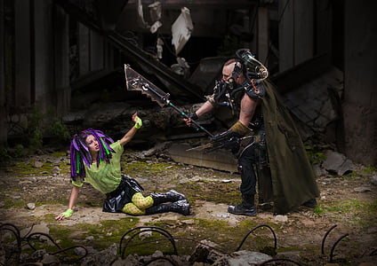 man holding weapon towards woman lying on ground shielding herself thumbnail