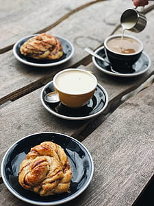 Two Brown and Black Ceramic Teacups Filled on Black Saucers thumbnail