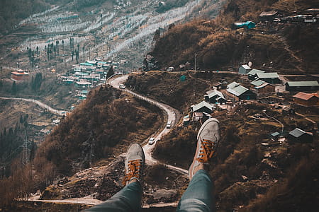 Person Wearing White Sneakers With Overlooking of Village on Hills thumbnail