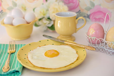 yellow ceramic mug near round yellow plate with fried egg on top thumbnail