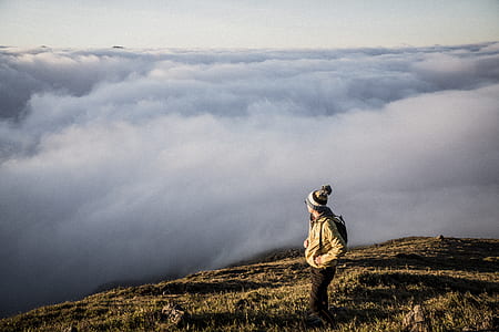 man standing on cliff with clouds overlooking thumbnail