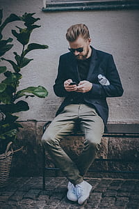 person sitting on table while using phone thumbnail