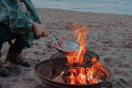 person grilling meat near beach thumbnail