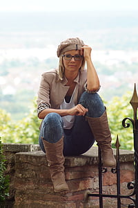 sitting woman wearing knit cap, white shirt, beige blazer, blue denim pants, and brown leather boots thumbnail